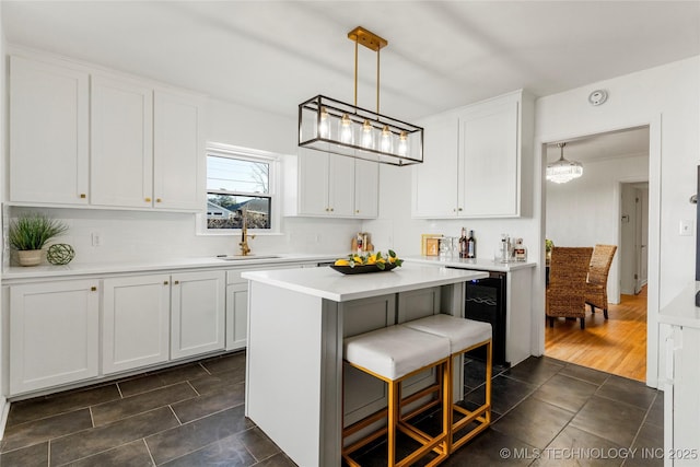 kitchen with a kitchen island, a breakfast bar, a sink, light countertops, and white cabinets