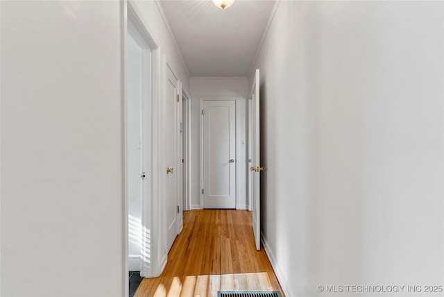 hall with baseboards, light wood-style floors, and ornamental molding