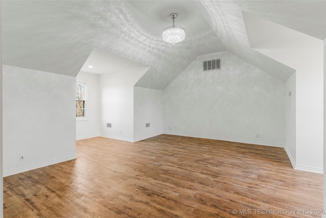 bonus room with wood finished floors, visible vents, baseboards, lofted ceiling, and a chandelier