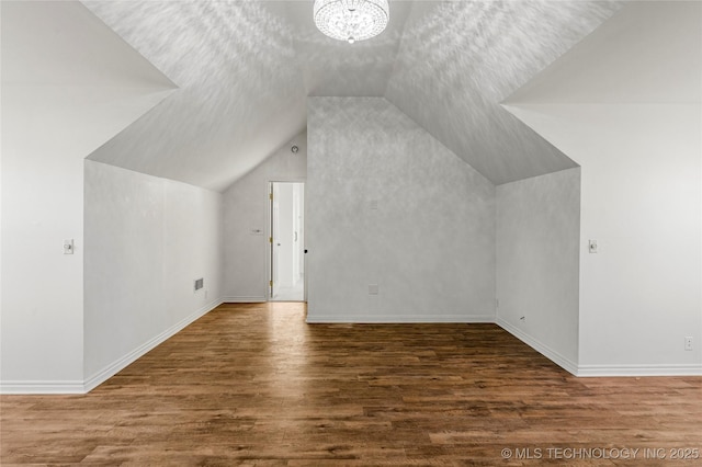 bonus room with an inviting chandelier, wood finished floors, baseboards, and vaulted ceiling