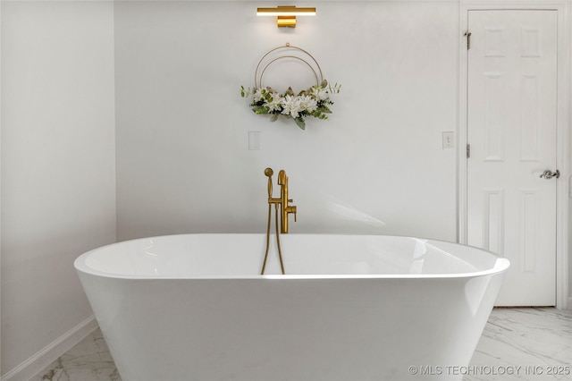 full bathroom featuring baseboards, a soaking tub, and marble finish floor