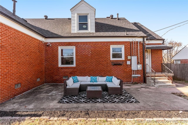 rear view of property with outdoor lounge area, a patio area, brick siding, and roof with shingles