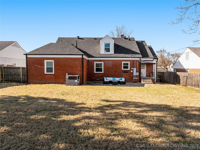 back of property with brick siding, a fenced backyard, a yard, and roof with shingles