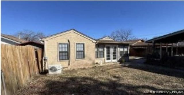 rear view of house featuring stucco siding and fence