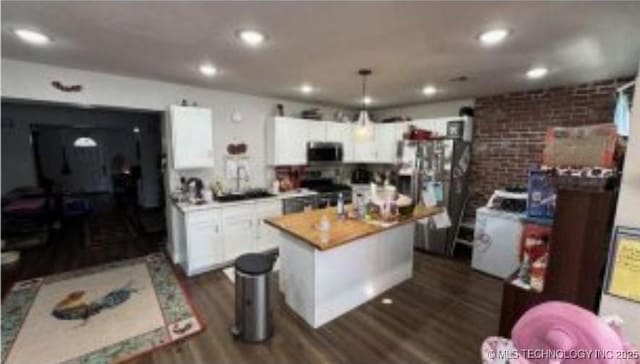 kitchen featuring a center island, dark wood finished floors, light countertops, appliances with stainless steel finishes, and white cabinetry