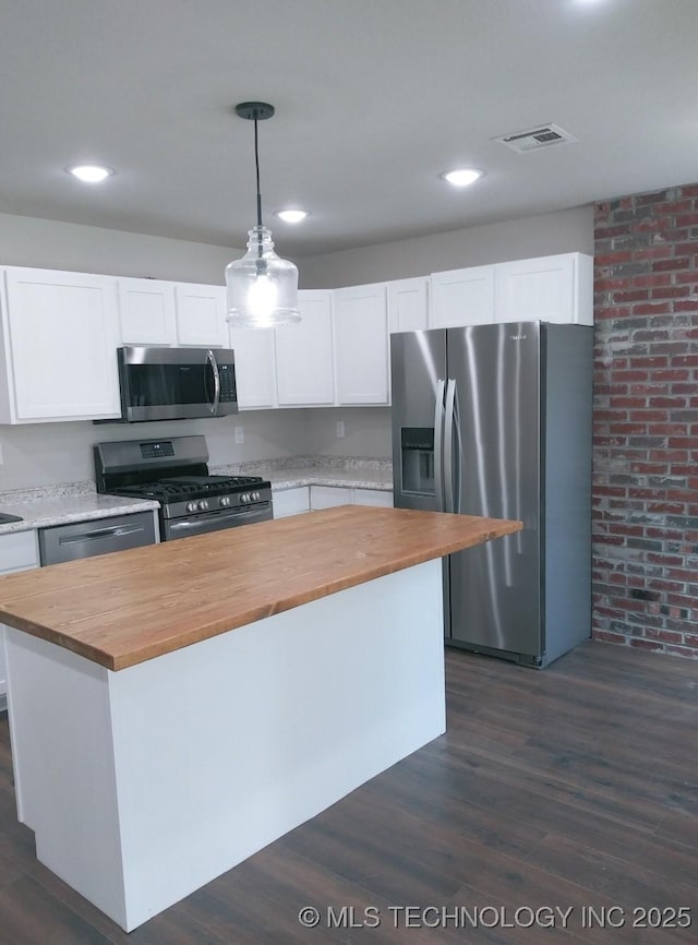 kitchen featuring white cabinets, butcher block countertops, and stainless steel appliances