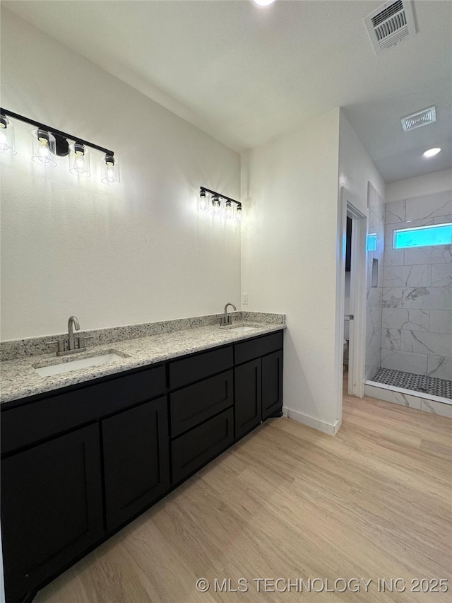 full bathroom with visible vents, a shower stall, wood finished floors, and a sink