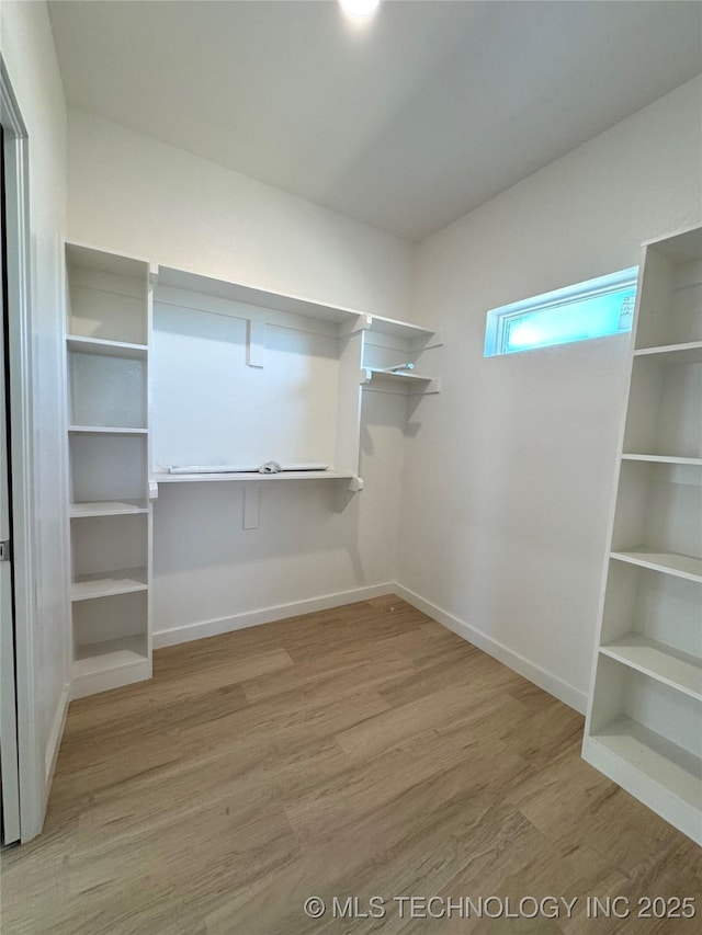 walk in closet with light wood-style floors