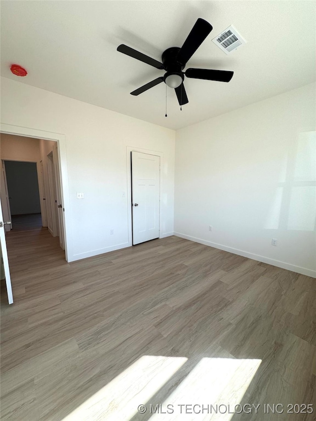 unfurnished bedroom featuring visible vents, baseboards, light wood-style floors, and a ceiling fan