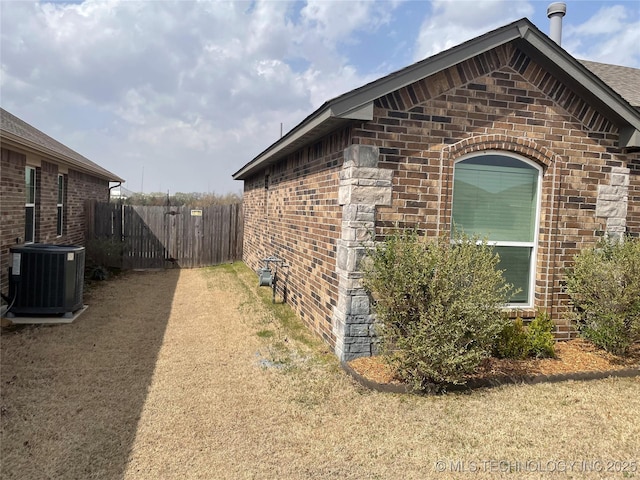 view of property exterior with brick siding, central AC, and fence