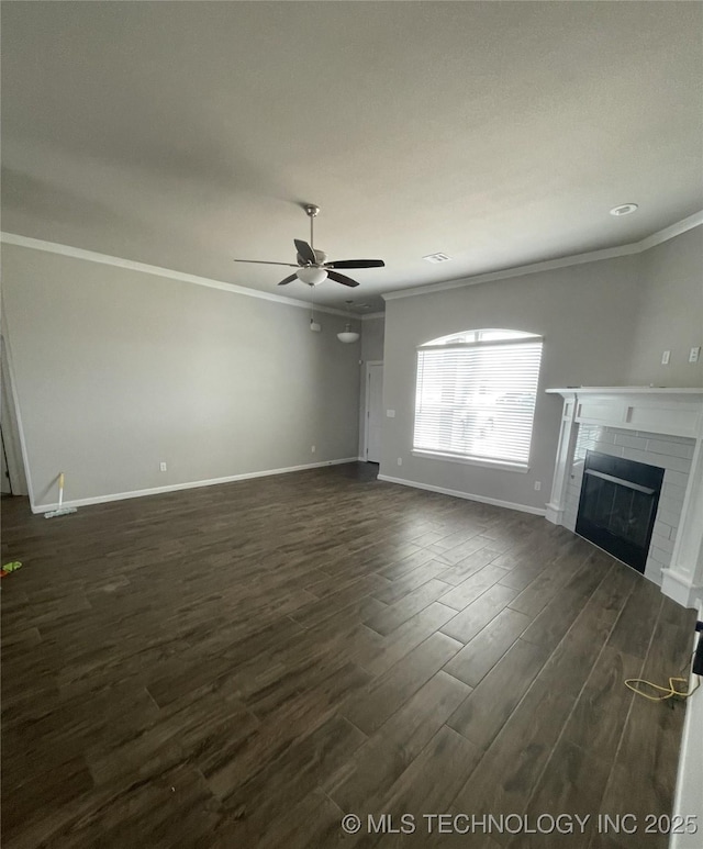 unfurnished living room featuring ornamental molding, a ceiling fan, a glass covered fireplace, dark wood-style floors, and baseboards