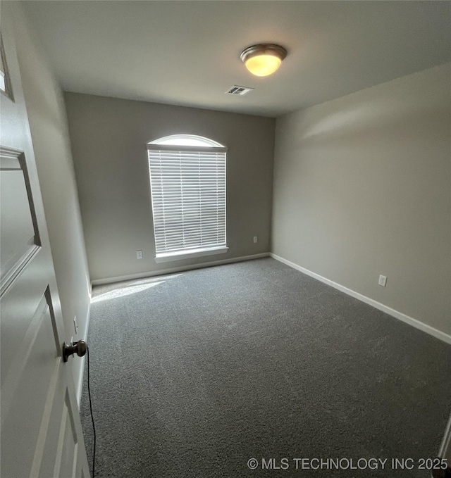 unfurnished room featuring baseboards, visible vents, and dark colored carpet