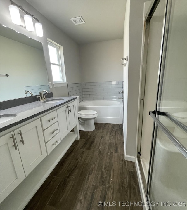 bathroom featuring wood finished floors, visible vents, a stall shower, a sink, and toilet