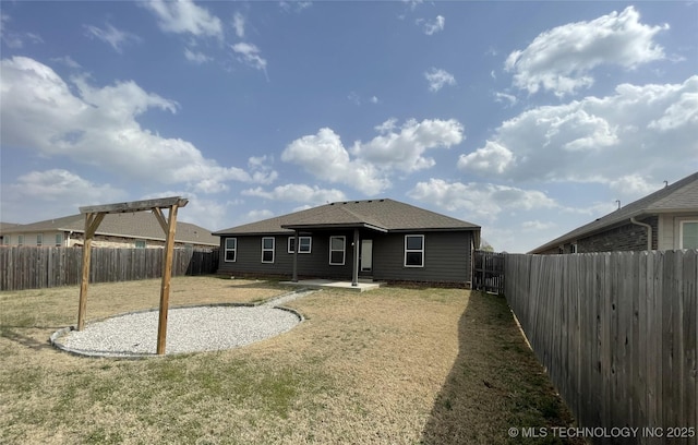 back of house with a yard, a shingled roof, a fenced backyard, and a patio area