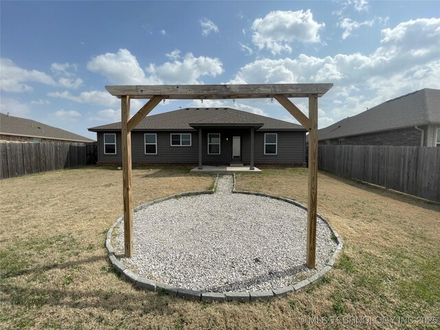 back of property with a yard, a fenced backyard, and a shingled roof