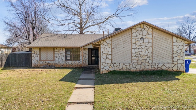 view of front of home featuring a front lawn, stone siding, and roof with shingles