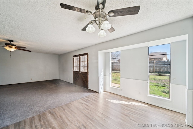 unfurnished room featuring carpet, wood finished floors, a ceiling fan, and a textured ceiling