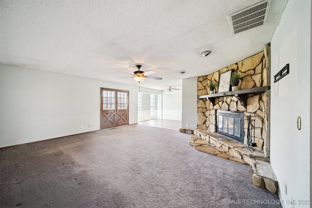 unfurnished living room with visible vents, carpet flooring, a fireplace, and a ceiling fan