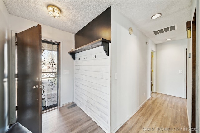 mudroom featuring visible vents, a textured ceiling, and wood finished floors