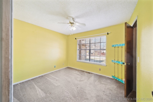 unfurnished room with baseboards, a textured ceiling, carpet, and a ceiling fan