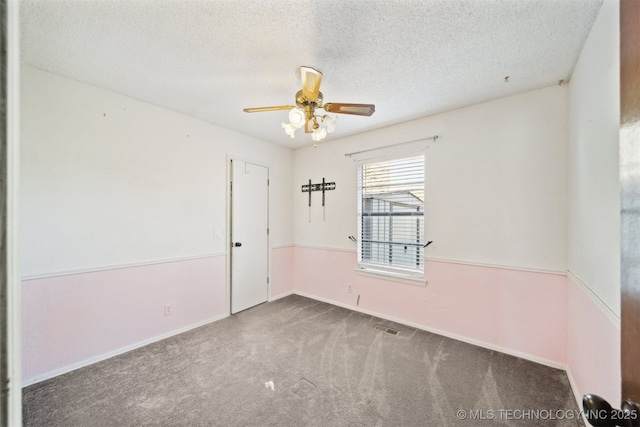 empty room featuring baseboards, a textured ceiling, a ceiling fan, and carpet