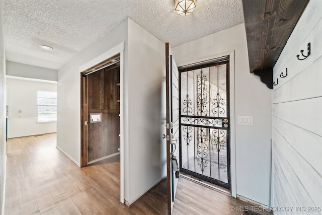 entryway featuring wood finished floors, baseboards, and a textured ceiling