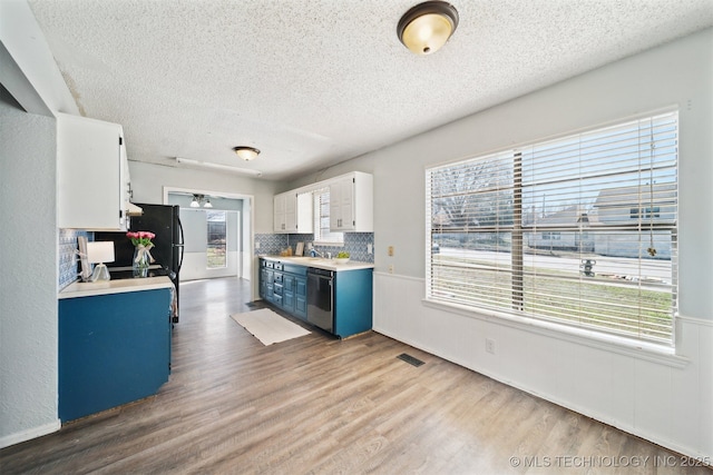 kitchen featuring visible vents, light countertops, wood finished floors, blue cabinets, and stainless steel dishwasher