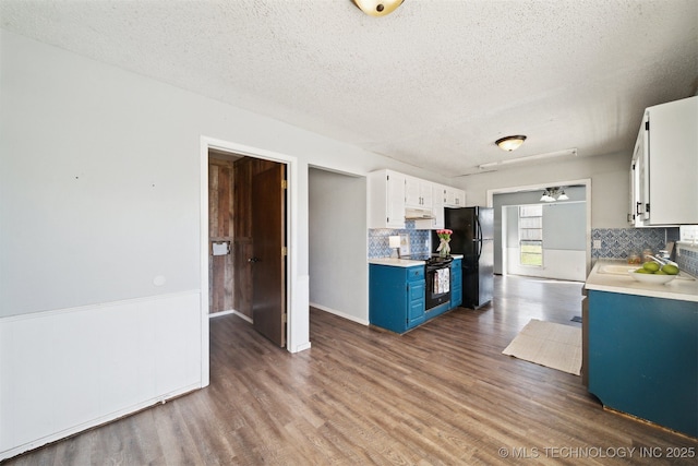 kitchen featuring blue cabinetry, wood finished floors, black range with electric cooktop, freestanding refrigerator, and light countertops