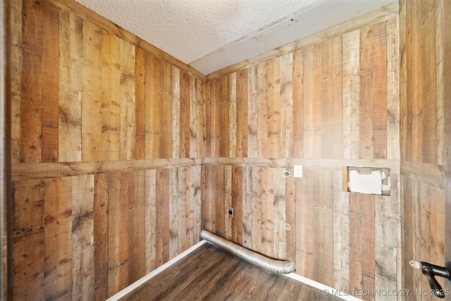 interior space featuring wood walls, a textured ceiling, and wood finished floors