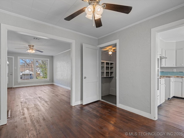 unfurnished living room with visible vents, ornamental molding, a ceiling fan, wood finished floors, and a textured wall