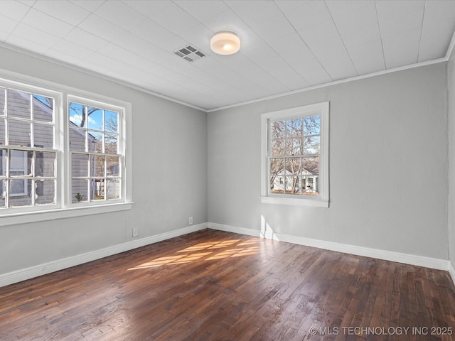 spare room with visible vents, ornamental molding, baseboards, and wood finished floors