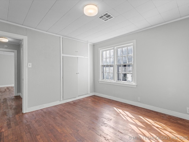 interior space featuring visible vents, baseboards, wood finished floors, and crown molding