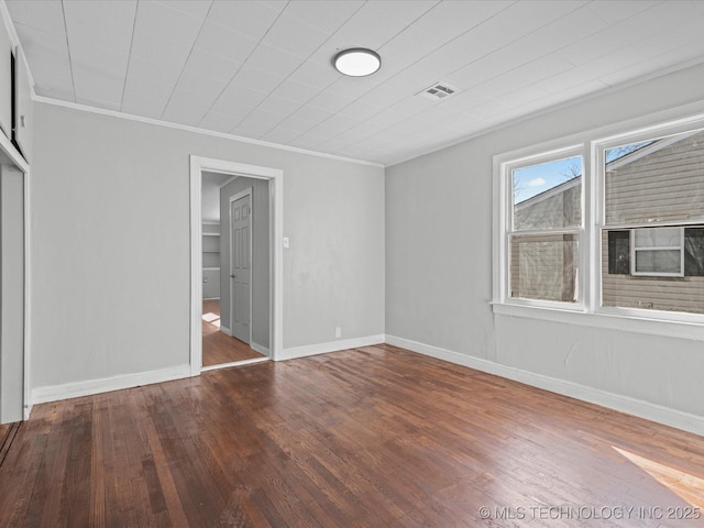 unfurnished bedroom featuring visible vents, wood-type flooring, baseboards, and crown molding