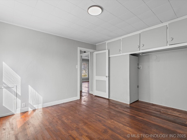 interior space featuring baseboards, dark wood finished floors, and ornamental molding