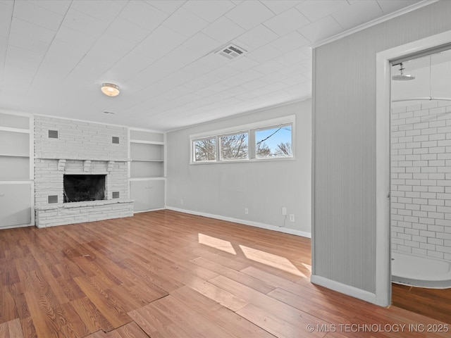 unfurnished living room featuring built in shelves, wood finished floors, visible vents, and baseboards