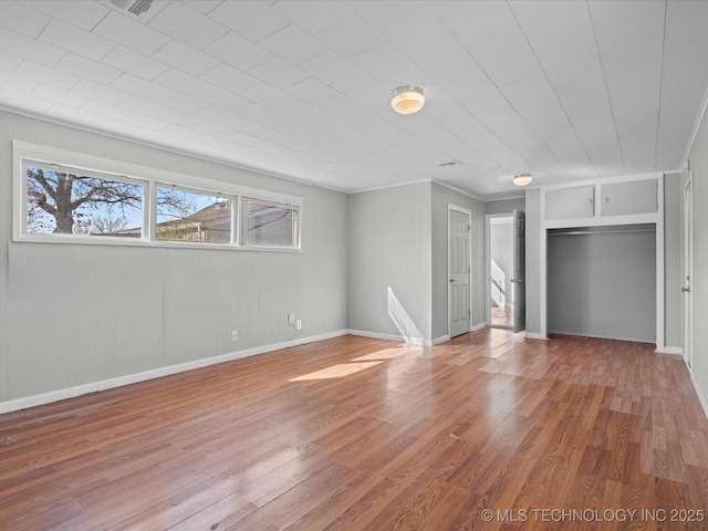 unfurnished living room featuring light wood-type flooring, baseboards, and ornamental molding