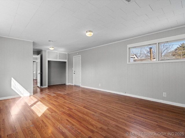 unfurnished living room with wood finished floors, baseboards, and ornamental molding