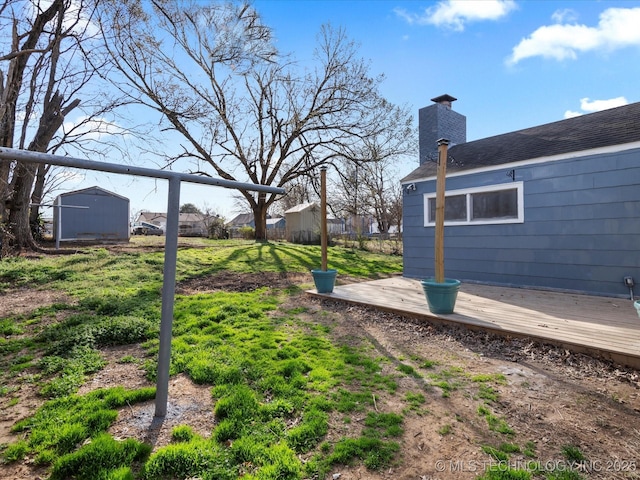 view of yard with an outbuilding, a wooden deck, a storage unit, and fence