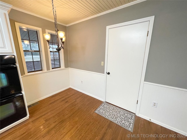 interior space with wood finished floors, a wainscoted wall, visible vents, ornamental molding, and a notable chandelier