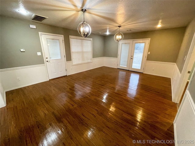 interior space with visible vents, wainscoting, french doors, wood finished floors, and a notable chandelier