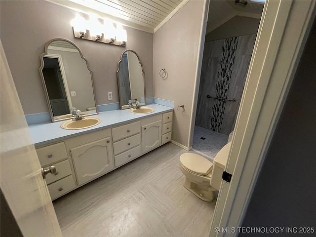 full bathroom featuring double vanity, a tile shower, toilet, and a sink