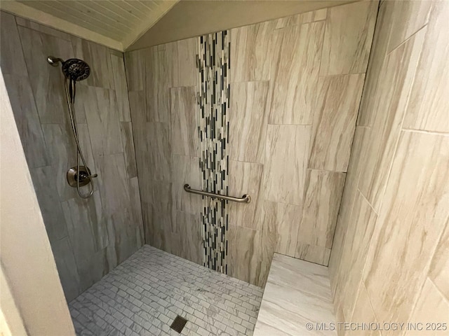 full bathroom featuring a tile shower and vaulted ceiling