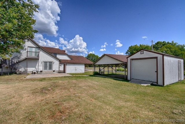 back of house featuring an outbuilding, stairway, a patio, and a yard