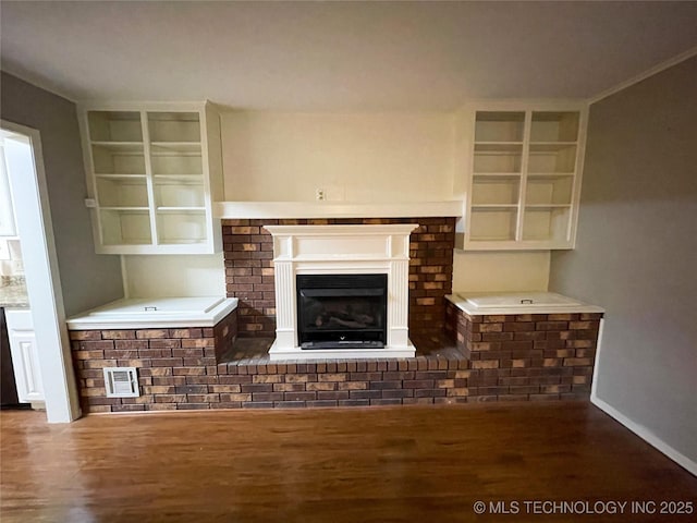 unfurnished living room featuring visible vents, a fireplace, baseboards, and wood finished floors