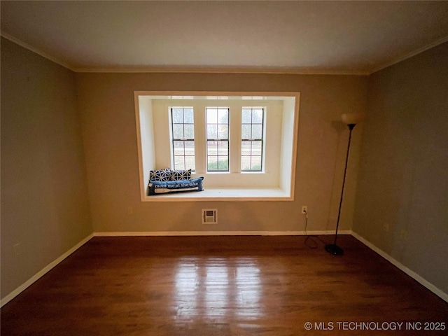 unfurnished room featuring visible vents, crown molding, baseboards, and wood finished floors