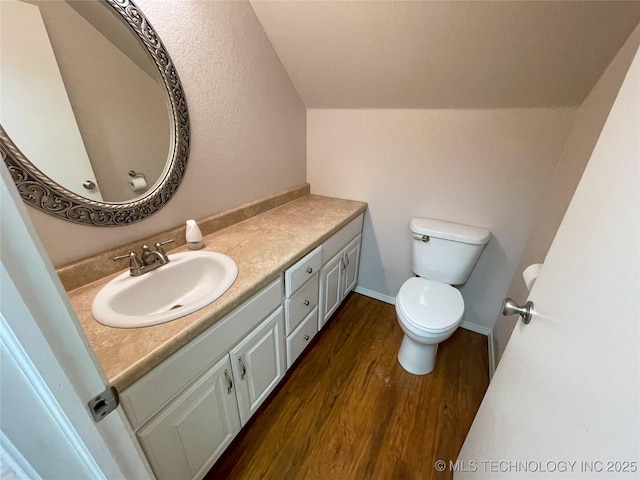 bathroom featuring toilet, lofted ceiling, wood finished floors, baseboards, and vanity