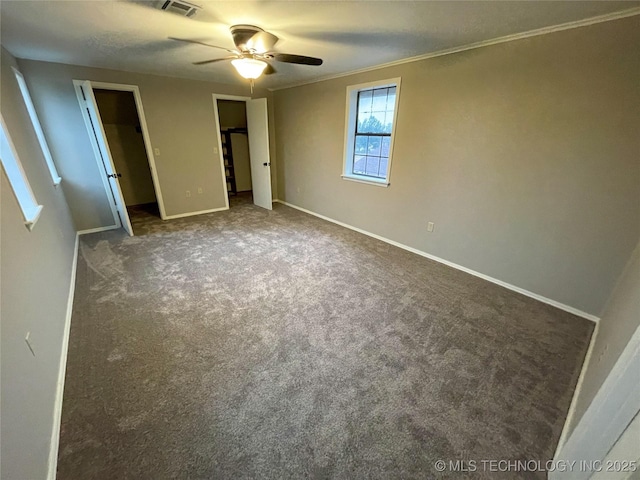 unfurnished bedroom with a ceiling fan, visible vents, baseboards, carpet floors, and ornamental molding