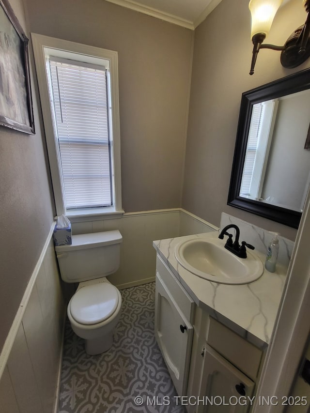 bathroom featuring crown molding, a wainscoted wall, toilet, tile patterned floors, and vanity