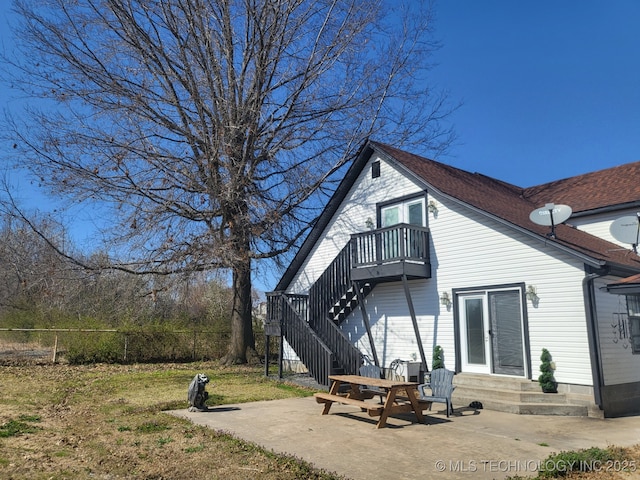 back of property featuring entry steps, fence, a balcony, stairs, and a patio area