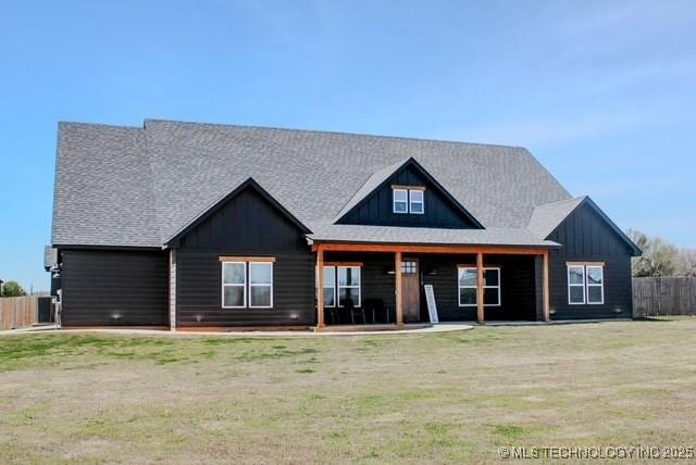 view of front of property with board and batten siding, a front yard, and fence